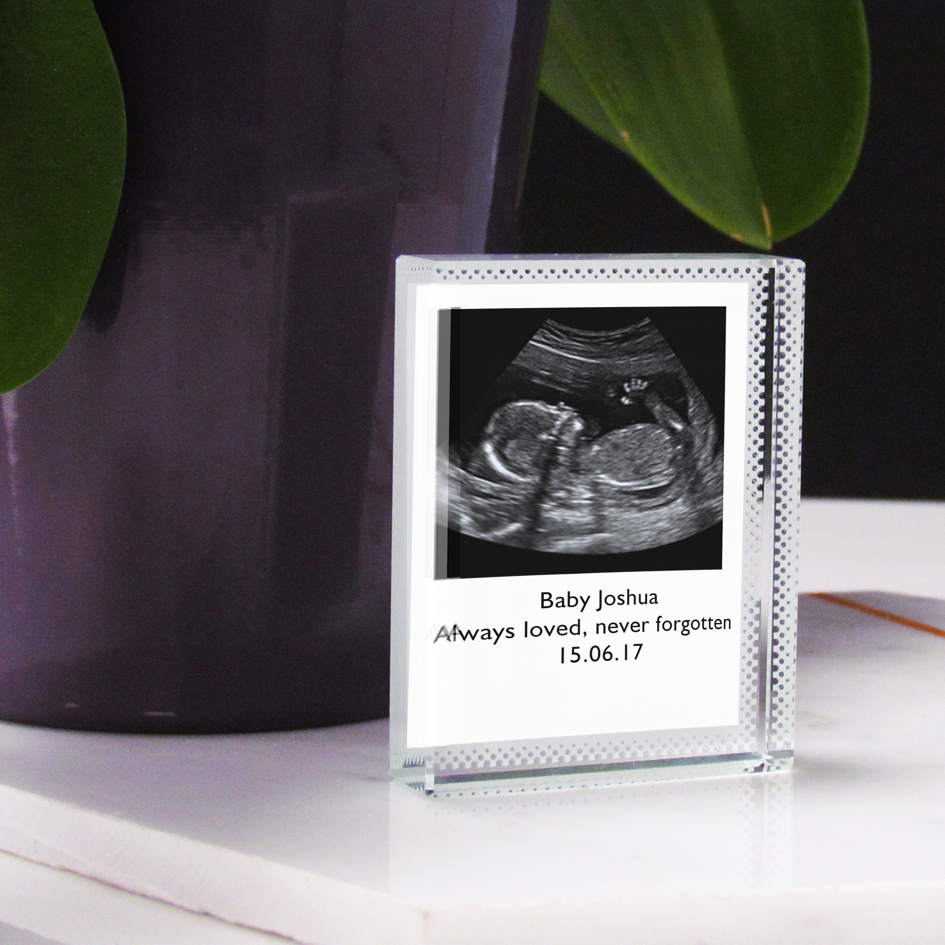 A clear acrylic photo block containing a printed black and white image of a baby, with a date '15.07.