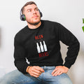 A person wearing a black Christmas jumper with a design featuring three beer bottles with antlers and red noses, text 'REINBEERS', and the brand name 'VÄXJÖ'. The jumper is on a white background.