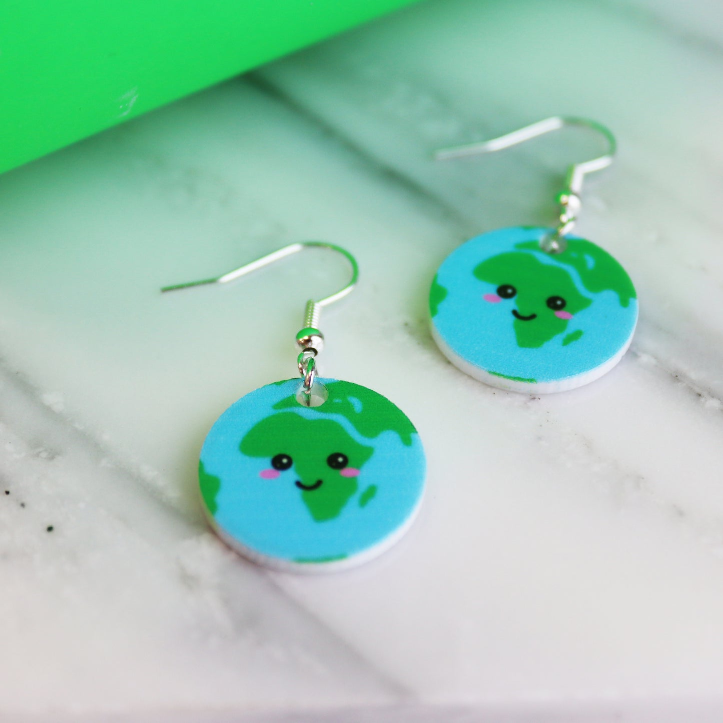 You are my whole world fun kawaii based earth earrings shown on marble background