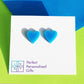 acrylic blue stud heart earrings available in two sizes shown on white earring backing card larger size shown