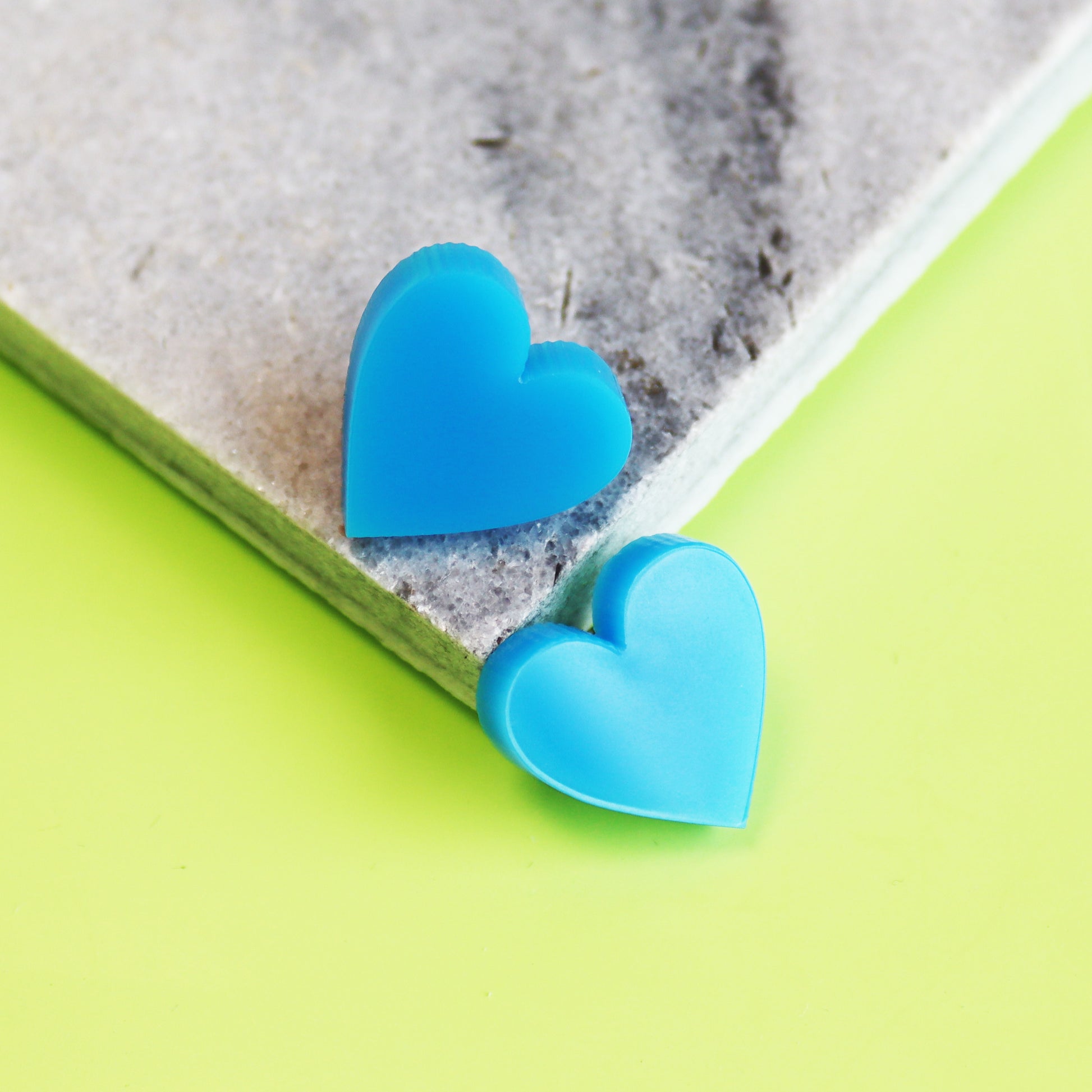 acrylic blue stud heart earrings shown in marble coaster