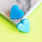 acrylic blue stud heart earrings shown in marble coaster close up
