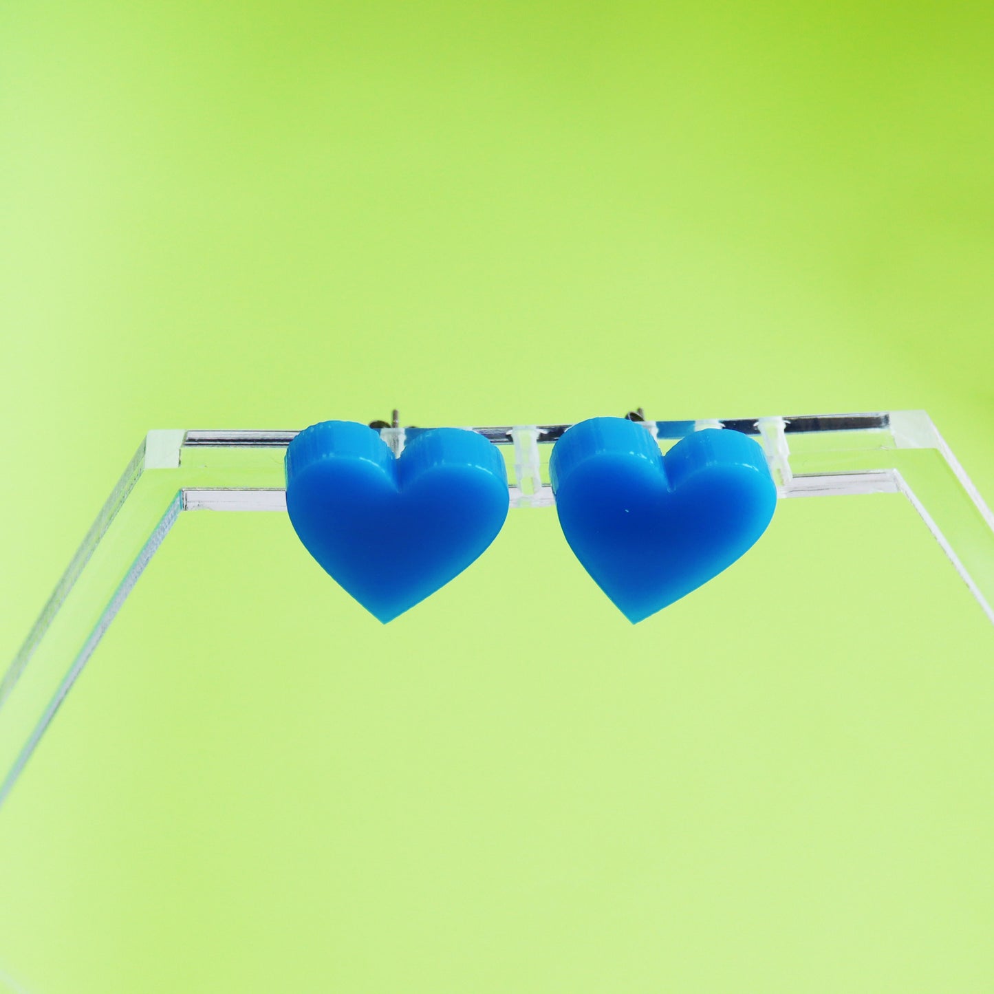 acrylic blue stud heart earrings shown on earring hanger