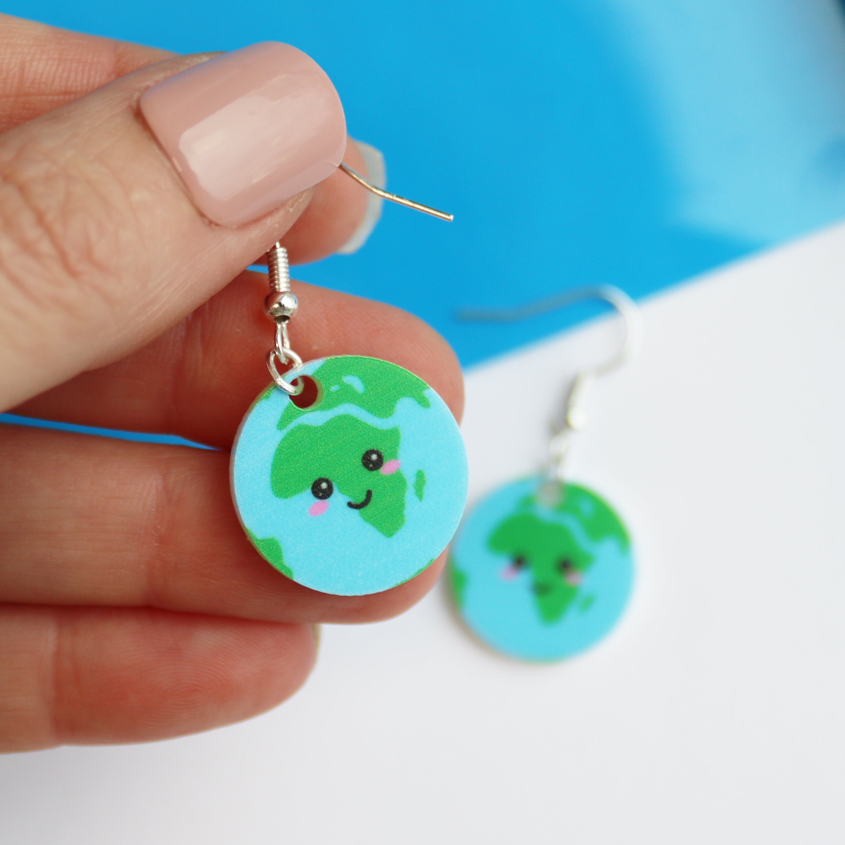 acrylic earrings printed with a kawaii earth shown in a woman's hand