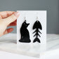 black cat and fish bone mismatches earrings cut from black acrylic shown hanging on backing display card