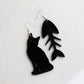 black cat and fish bone mismatches earrings cut from black acrylic with the bone earring on marble background