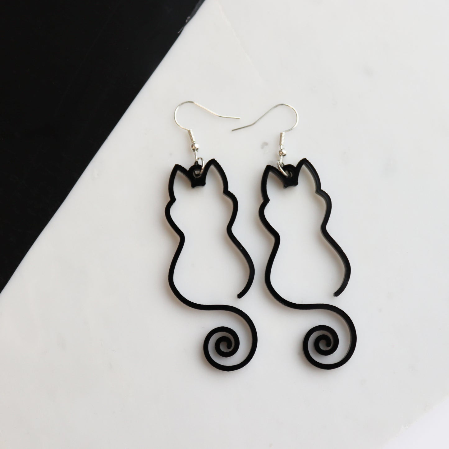 black cat outline pair of earrings acrylic outline cat earrings shown on white and black background