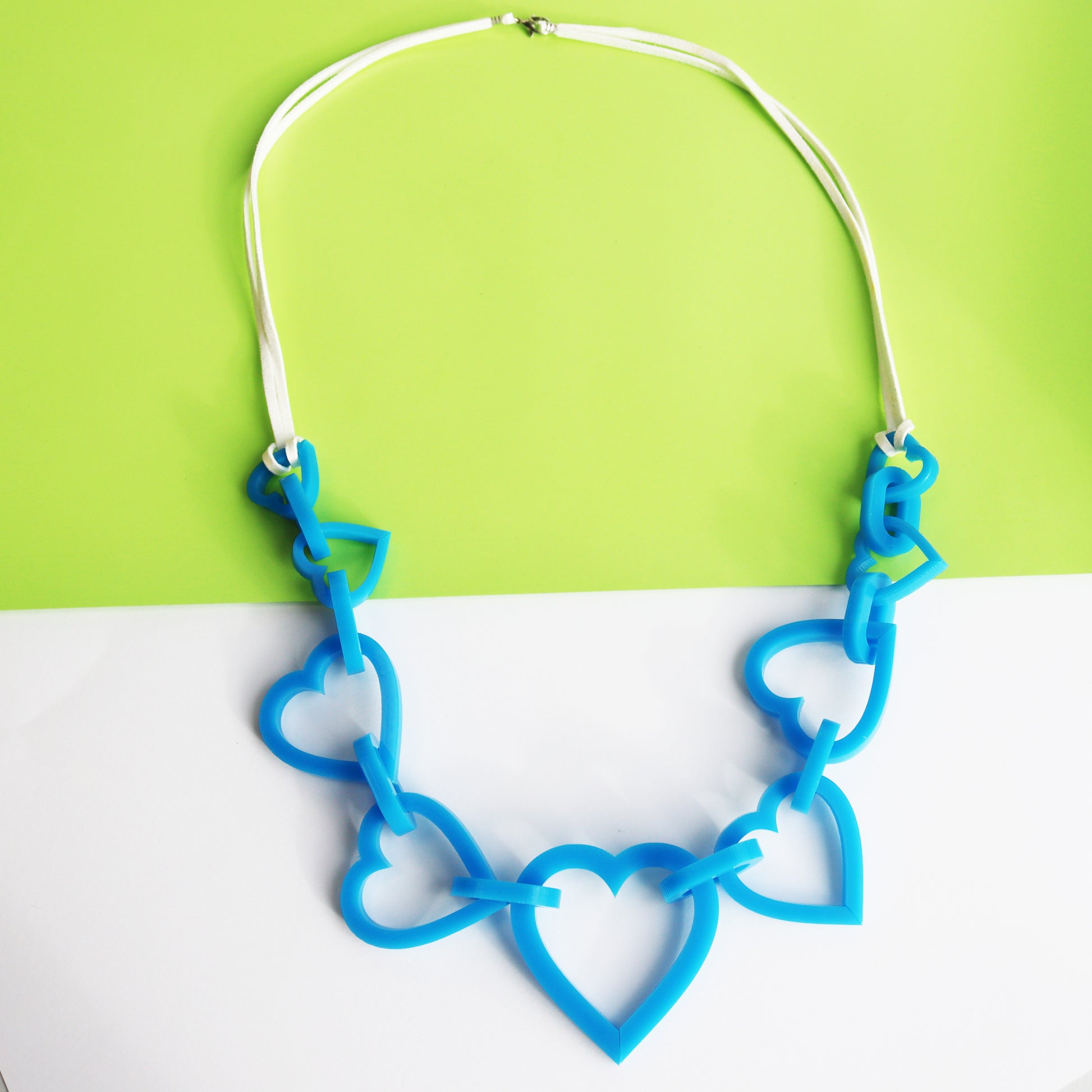 bright blue necklace cut from acrylic heart shapes and linked together with blue links on a leather chain