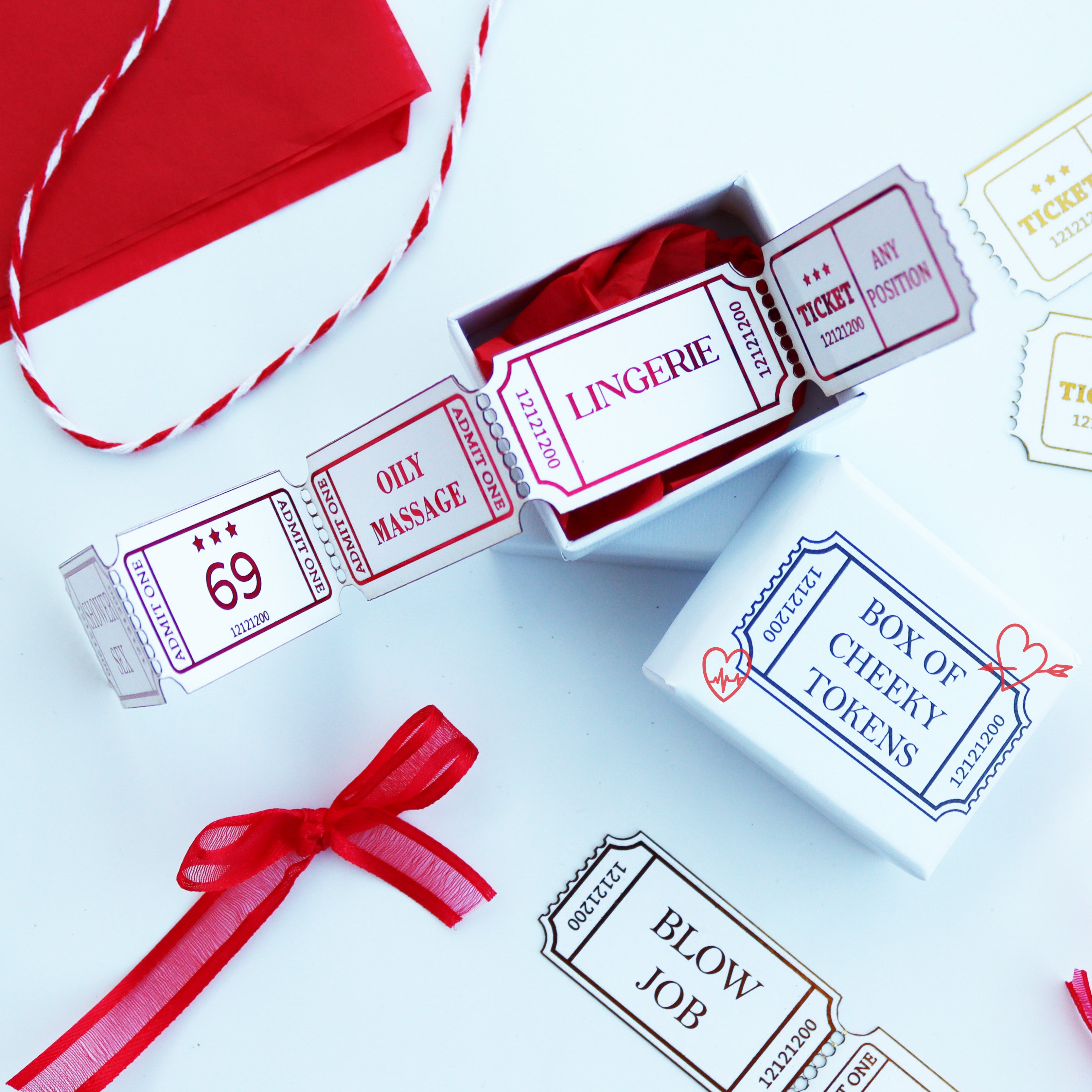 The image shows a collection of personalized cheeky ticket stub tokens with various naughty phrases printed on them, presented in a small white box. The tokens are in the form of movie or event tickets, with options for customization such as adding a number, name, or message.