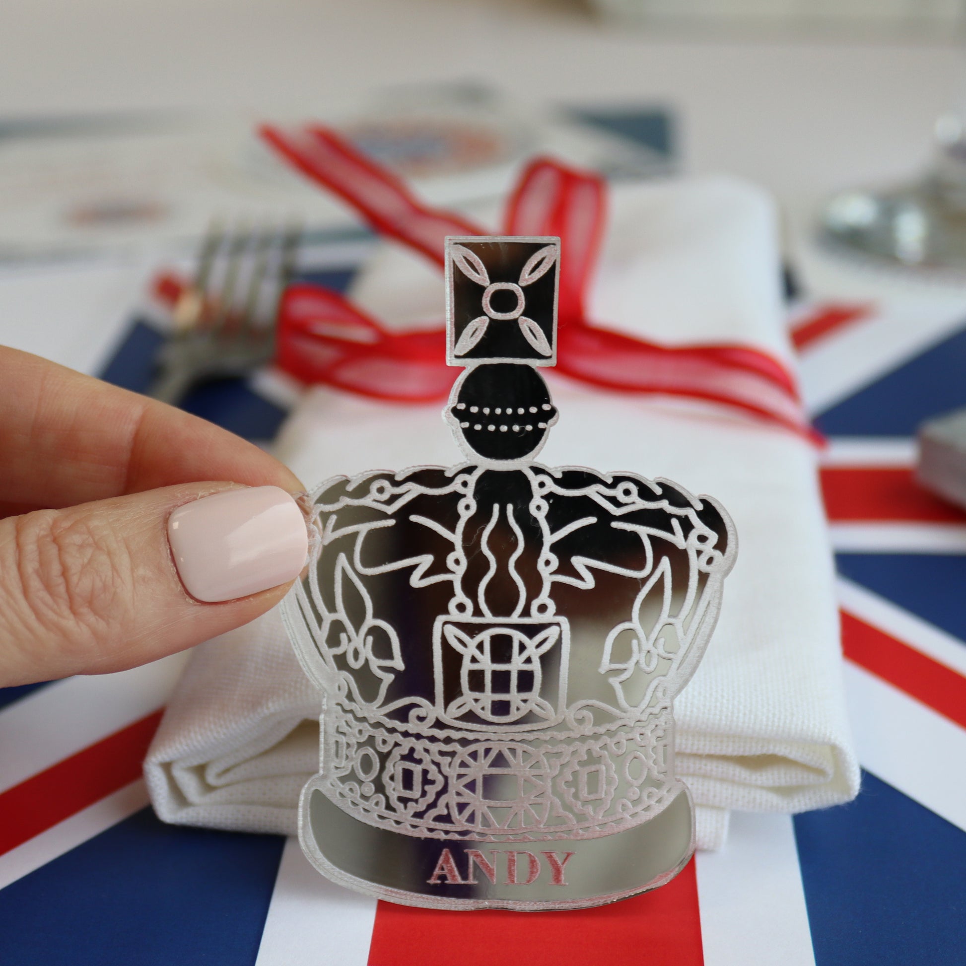 close up of table setting which is cut and engraved from silver acrylic into the shape of a crown as a personalised place setting for King's Coronation