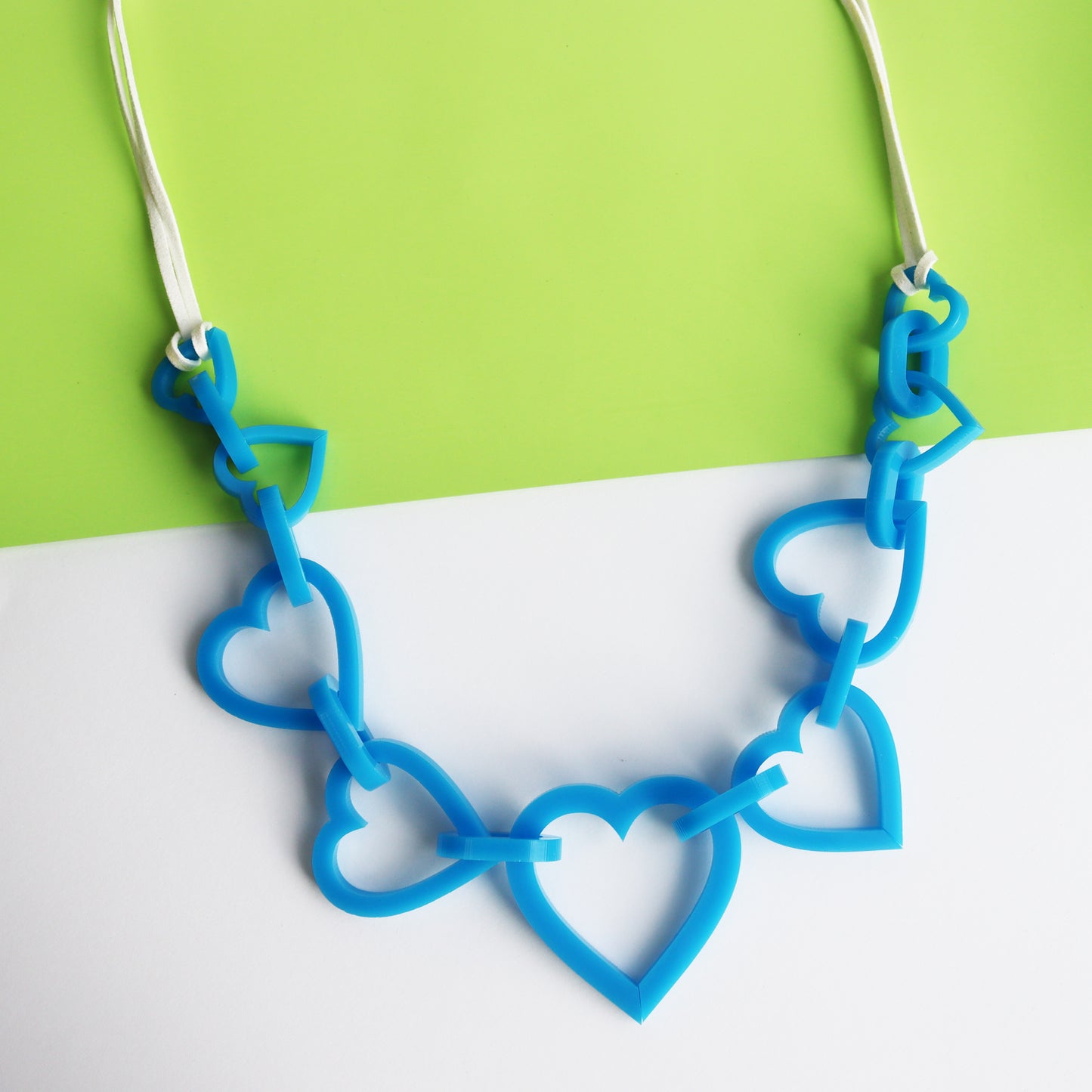colourful large statement blue acrylic neckalce cut into the shape of heart and linked together with blue acrylic loops