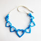 heart acrylic blue necklace shown on white background