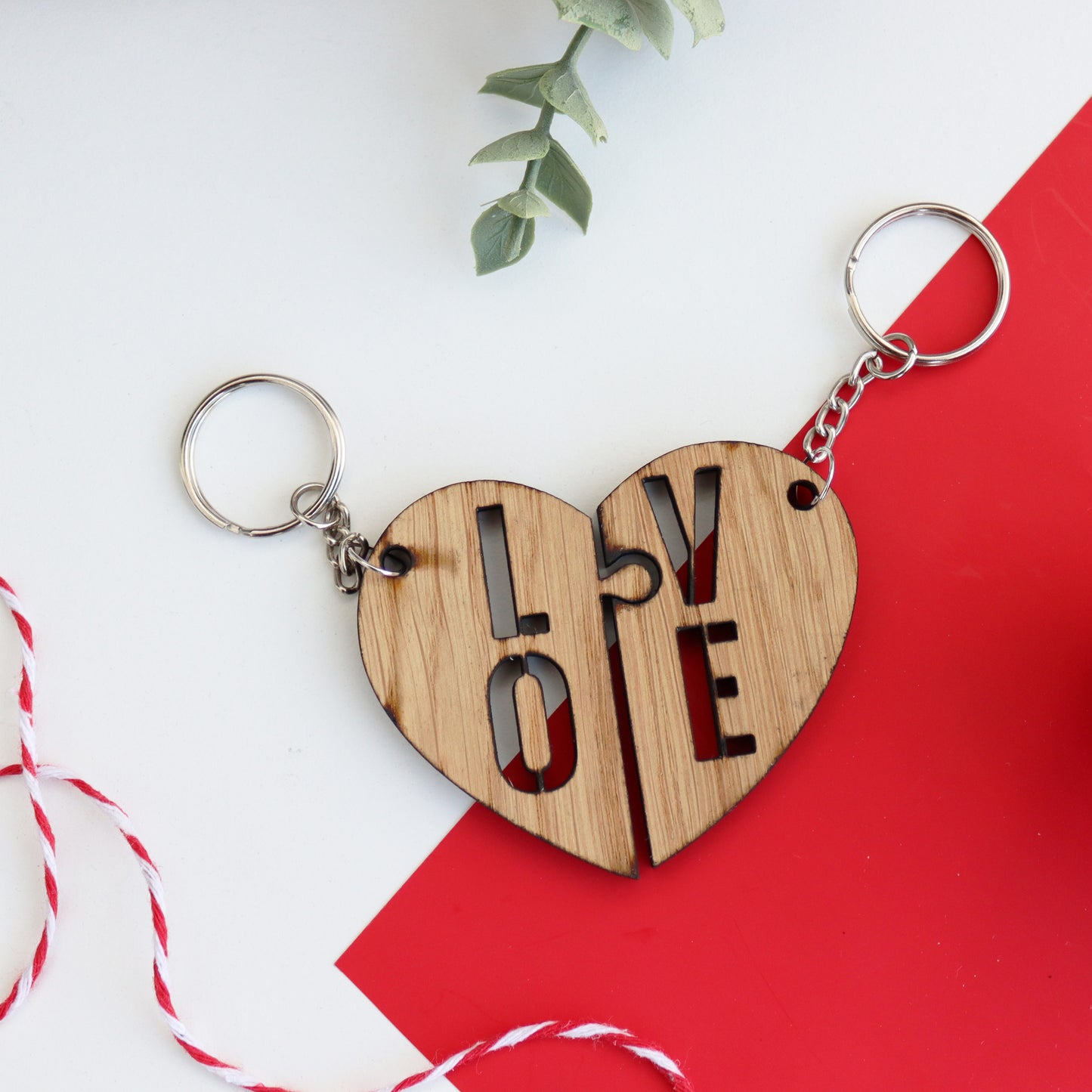 heart keyring split into with LOVE written between the two couples keyring set on simple white and red background