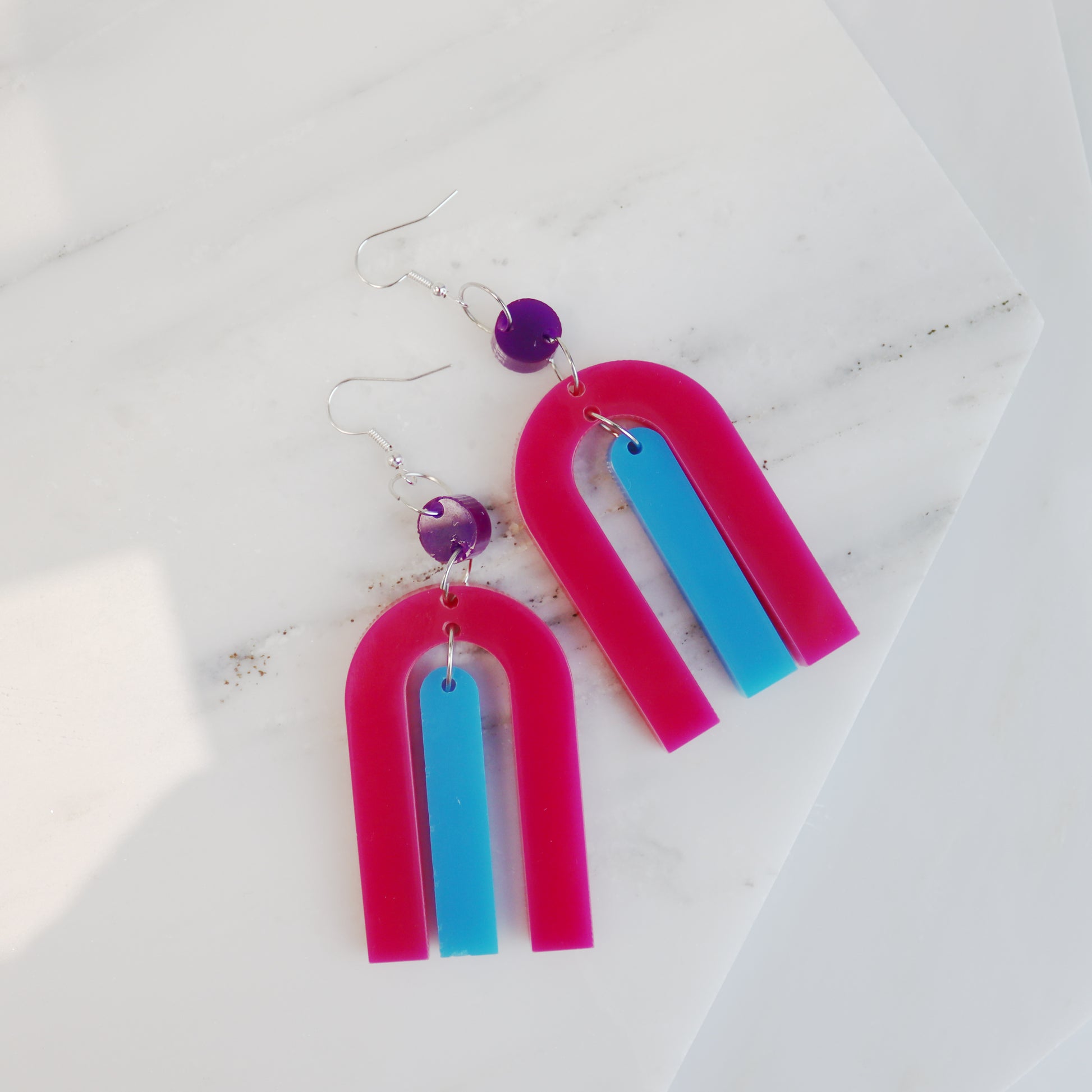 modern bright and colourful geometric arch dangle earrings cut from a purple, pink and turquoise acrylic