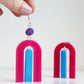 modern bright and colourful geometric arch dangle earrings cut from a purple, pink and turquoise acrylic shown hanging from a hand