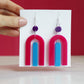 modern bright and colourful geometric arch dangle earrings cut from a purple, pink and turquoise acrylic shown hanging on backing card image 2