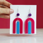 modern bright and colourful geometric arch dangle earrings cut from a purple, pink and turquoise acrylic shown hanging on backing card image 2