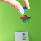 printed acrylic colourful handmade acrylic earrings with one earring being held