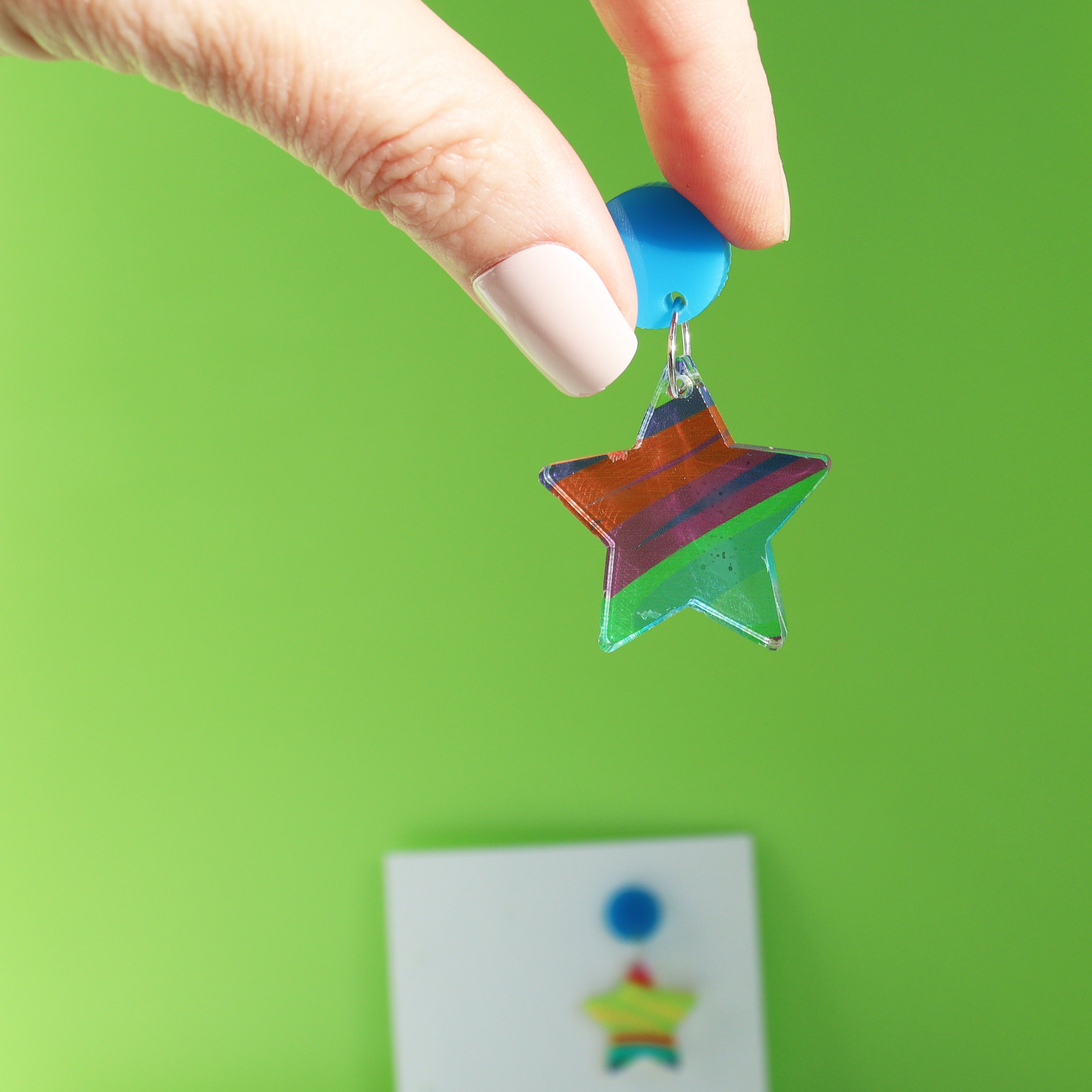 printed acrylic colourful handmade acrylic earrings with one earring being held