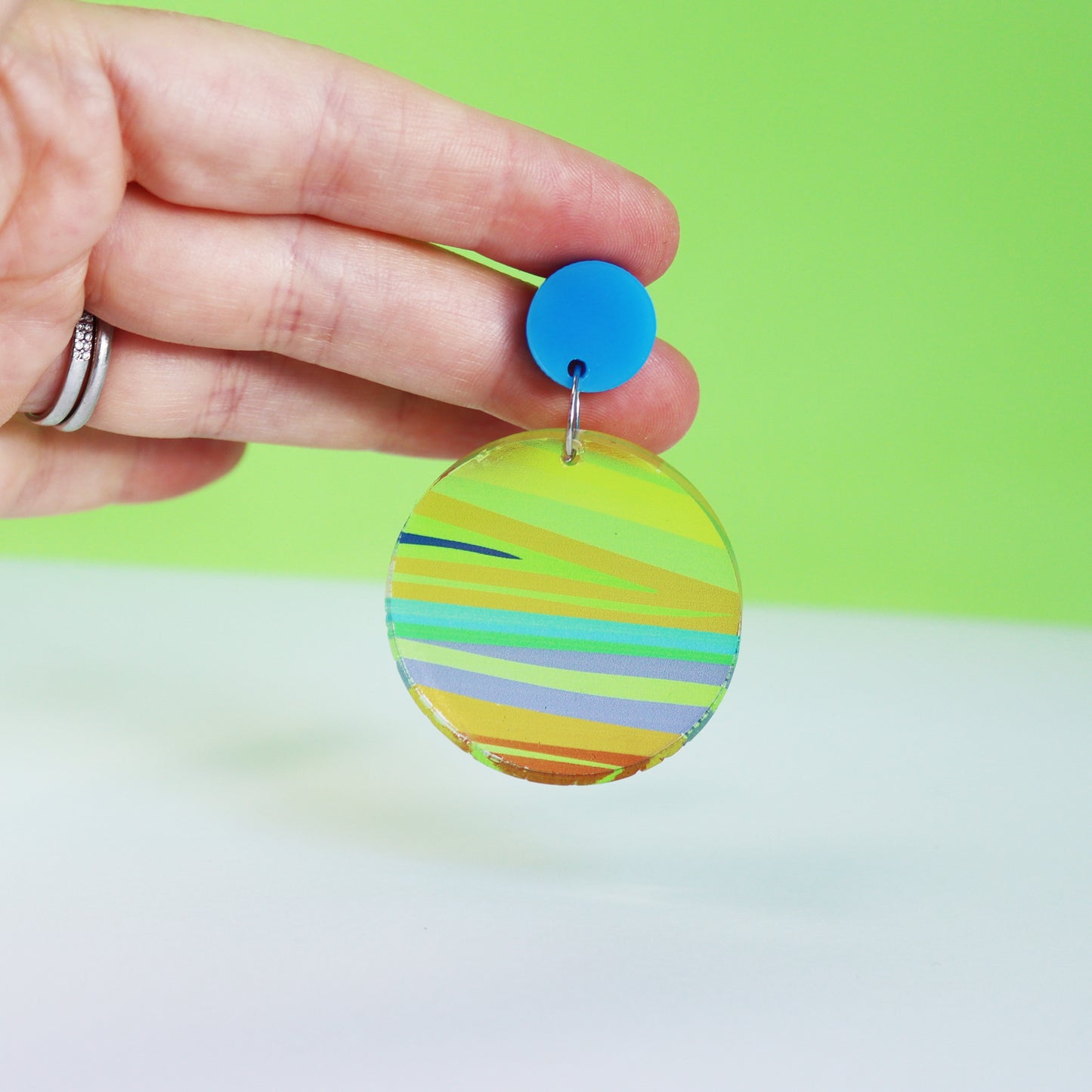 printed acrylic colourful mismatch circle earrings shown in a hand