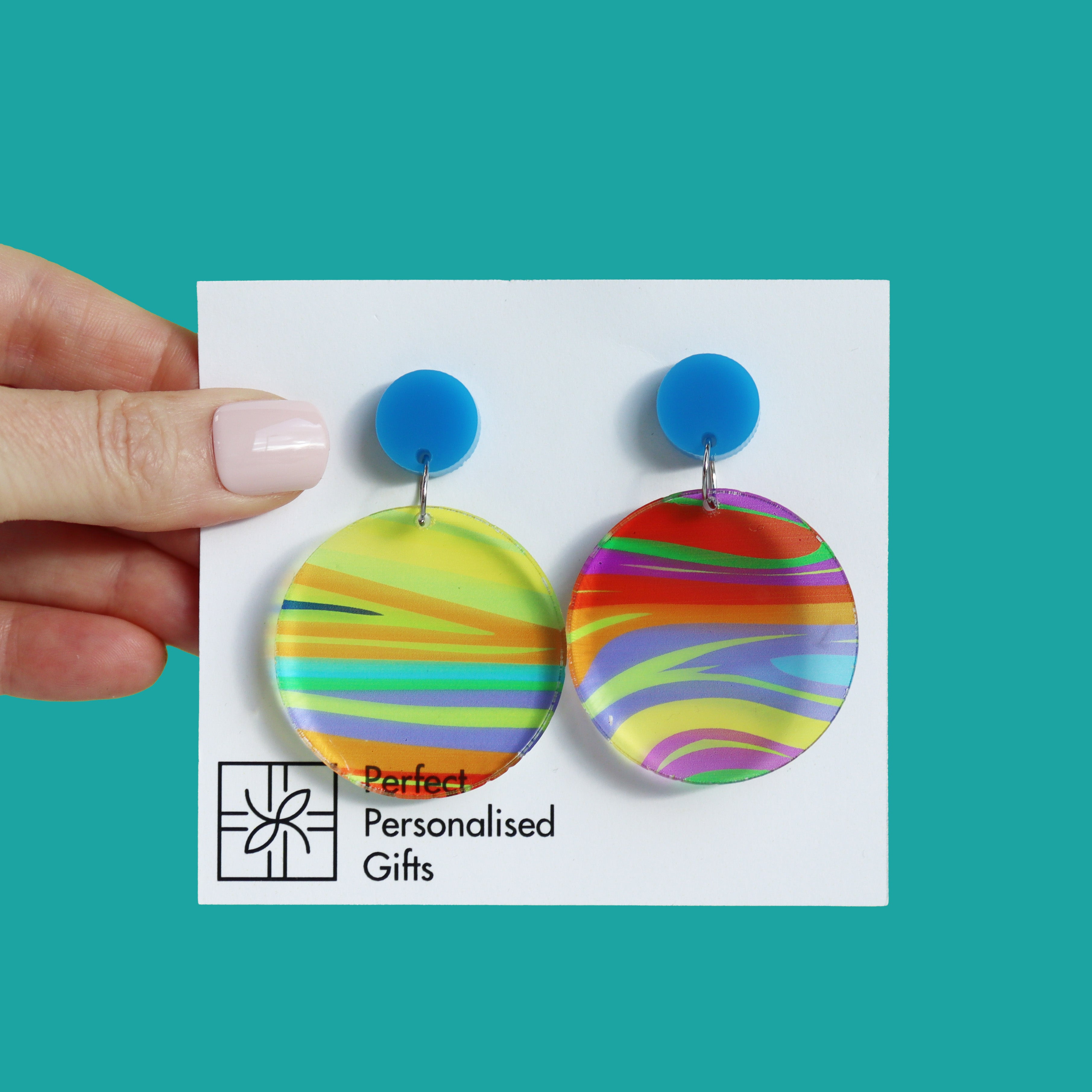 printed acrylic colourful mismatch earrings that have a round blue acrylic stud top and hanging printed acrylic circle hanging on a turquoise