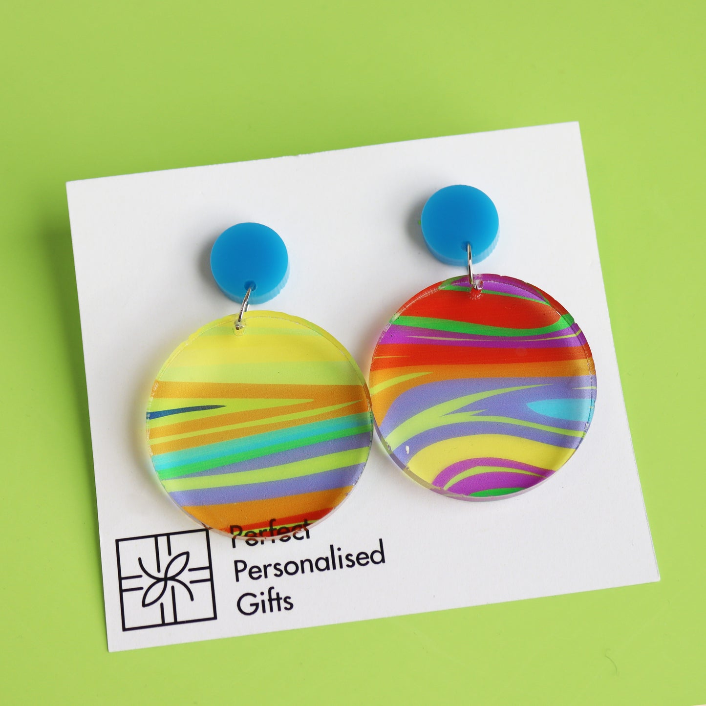 printed acrylic colourful mismatch earrings that have a round blue acrylic stud top and hanging printed acrylic circle hanging on a white card background
