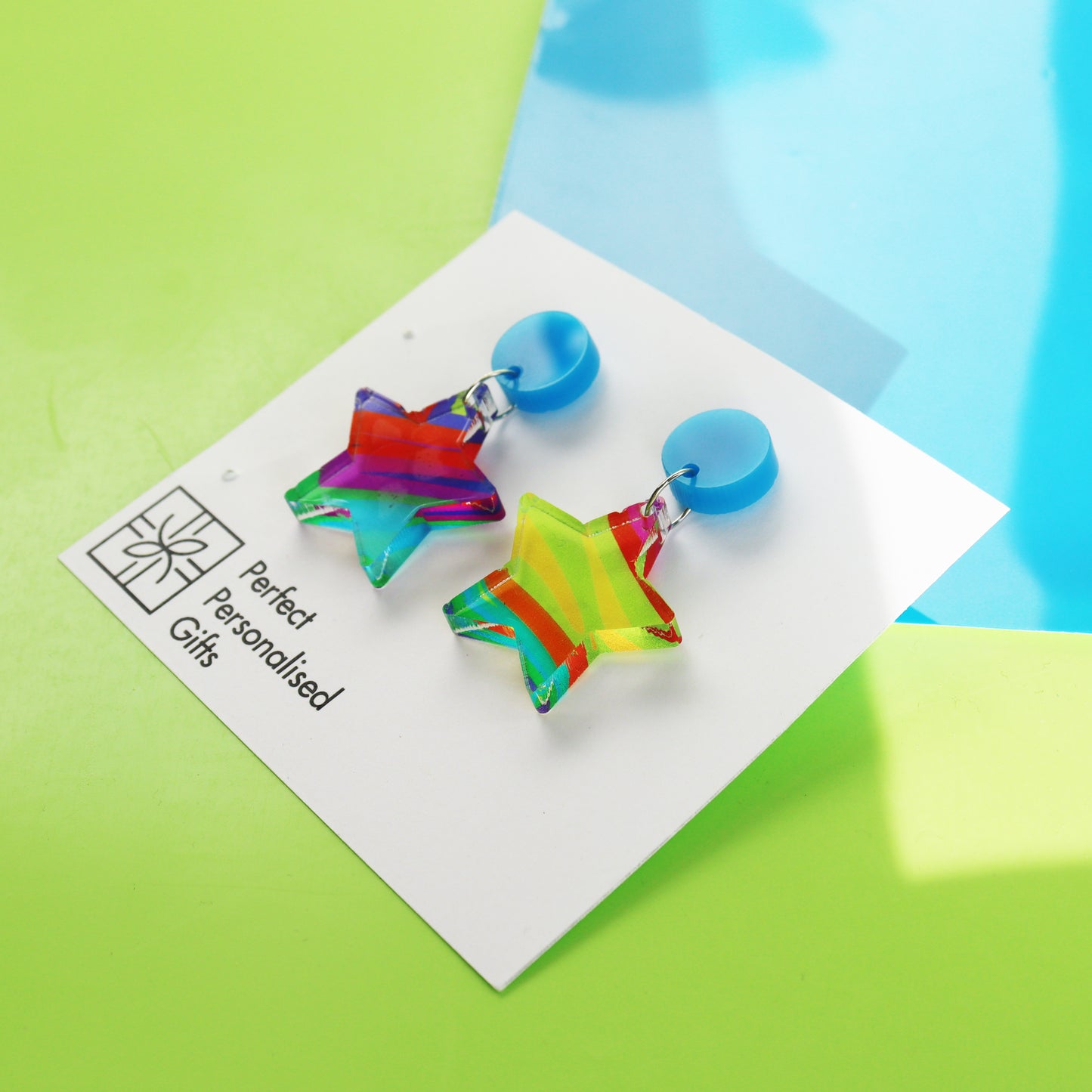 printed acrylic colourful mismatch earrings that have a round blue acrylic stud top and hanging printed acrylic star