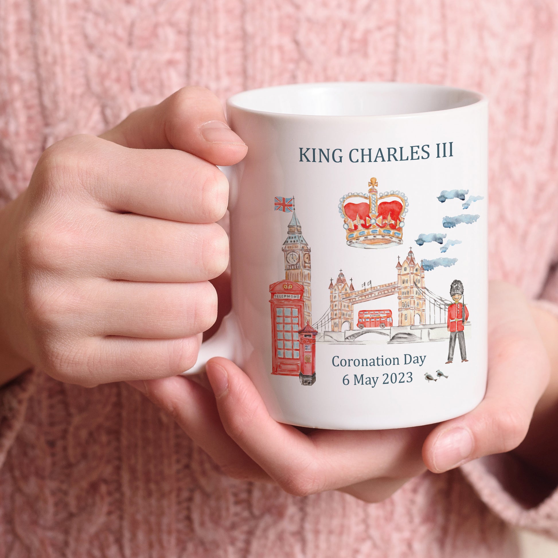 white mug printed with watercolour images of London and the words King Charles III coronation 6 May 2023 commemorative mug